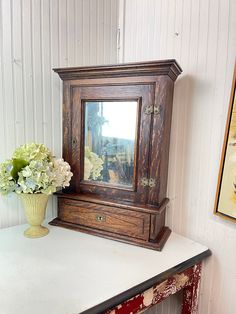 a vase with flowers sitting on top of a table next to a mirror and shelf