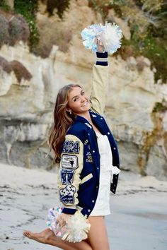 a beautiful young woman standing on top of a beach holding a pom pom