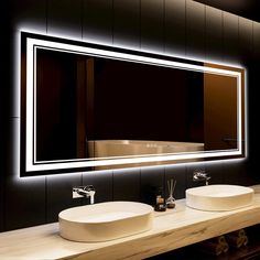 a bathroom with two sinks and a large mirror on the wall above it that is illuminated by lights