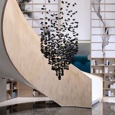 a spiral staircase with lots of black objects hanging from it's side and bookshelves in the background