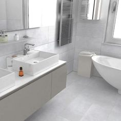 a white bathroom with two sinks and a bathtub