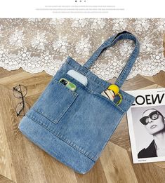 a blue jean purse sitting on top of a wooden floor next to an eyeglass case