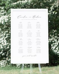 a white sign sitting on top of a wooden easel in front of a lush green field