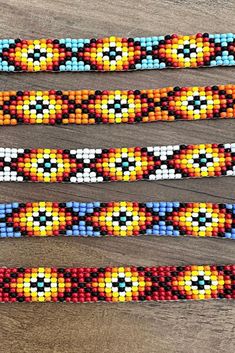 three colorful beaded bracelets sitting on top of a wooden table next to each other