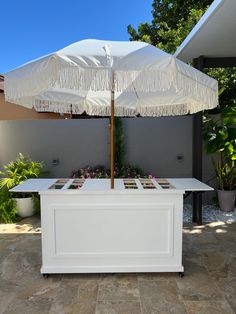 an umbrella that is sitting on top of a table in front of some plants and flowers