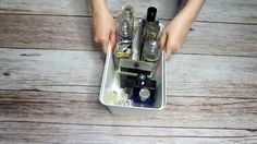 a person holding an empty container filled with liquor and other alcohol bottles on top of a wooden floor