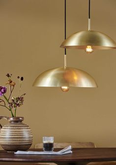 three lights hanging from the ceiling above a table with flowers in vases on it