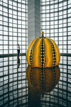 a large orange object sitting in the middle of a room next to a person walking