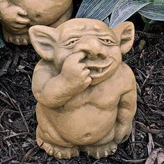 two clay garden gargons sitting on the ground next to each other, one with its mouth open