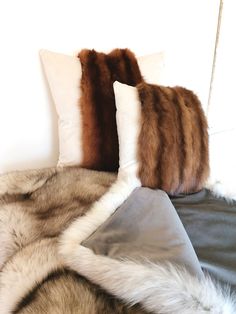 three pillows on top of a bed covered in fur