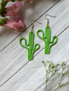 the green cactus earrings are next to pink flowers