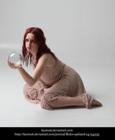 a woman sitting on the ground holding a glass ball