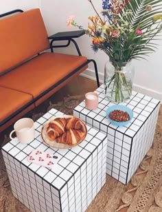 two coffee tables with food on them in front of a couch and flower vases