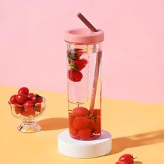 a blender filled with cherries and strawberries next to a bowl of cherries