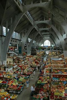 an indoor market with lots of produce and people