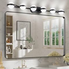 a bathroom with a sink, mirror and lights on the wall next to it in front of a window