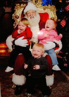 three children are sitting in front of santa claus's chair with his mouth open