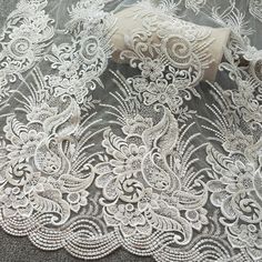 white lace with flowers and leaves on a gray background, close up view from above