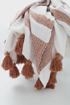 an orange and white blanket with tassels on it's ends is shown