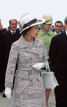 a woman in a coat and hat walking with other people