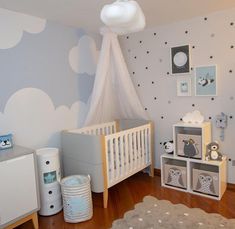 a baby's room decorated in gray and white with clouds on the wall, teddy bear crib