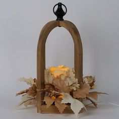 a candle is lit in a wooden lantern with leaves on the sides and around it