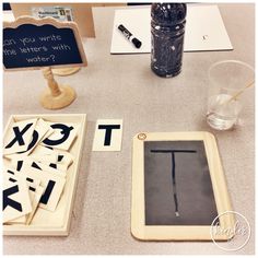 a table topped with different types of magnets and wooden letters next to a bottle of water