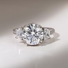 a three stone diamond ring on a white surface