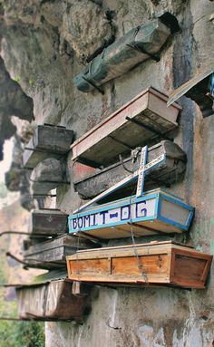 several wooden boxes are stacked on top of each other in front of a rock wall