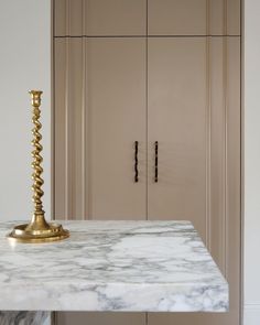 a marble counter top in a kitchen with gold accents on the base and cupboards behind it