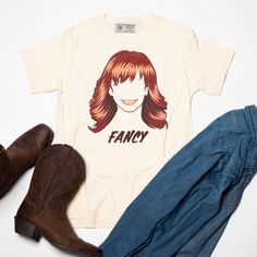 This tee features the legendary Reba McEntire herself, looking as beautiful and sassy as ever, with her classic hit "Fancy" immortalized in big bold letters right on the front. So whether you're a true Southern belle or just a fan of good ole' fashioned country music, the Fancy Country Tee is the perfect addition to your wardrobe. Yeehaw! True to size fit. 100% Cotton (Pre-Shrunk) in Natural Color. Designed and printed in Nashville, TN with water-based ink. Country Tees, Bold Letters, Reba Mcentire, Good Ole, Music City, Southern Belle, Running Tops, Virtual Closet, A Fan