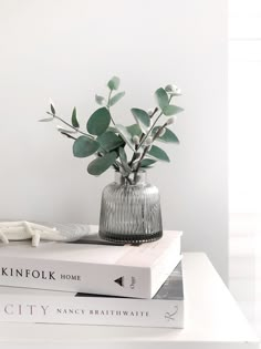 two books are stacked on top of each other next to a vase with flowers in it