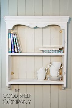 a white shelf with books and cups on it