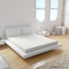 a white bed sitting on top of a hard wood floor next to a large window