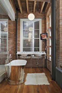 an old fashioned bathroom with exposed brick walls and wood flooring, including a claw foot tub