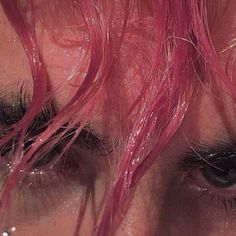 a close up of a person's eye with pink hair and black eyeshades