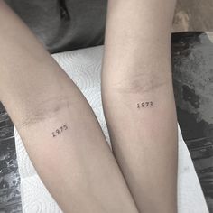 two people with matching tattoos on their arms, both have numbers tattooed on the arm