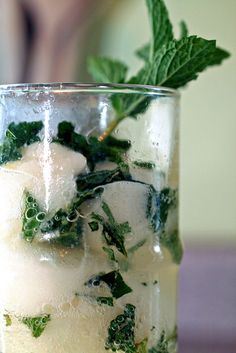 a glass filled with ice and mint on top of a table