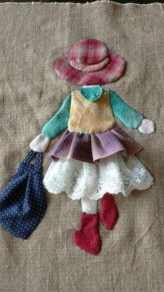 the doll is wearing a hat, dress and boots with two purses next to it