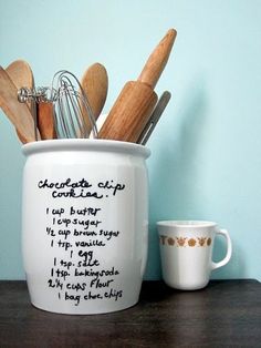 a coffee cup filled with wooden spoons and utensils on top of a table