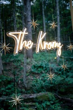 a sign that says the krong hanging from strings in front of some trees