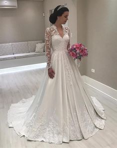 a woman in a white wedding dress holding a pink bouquet and posing for the camera