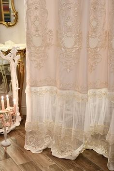 a white shower curtain sitting on top of a wooden floor next to a candle holder