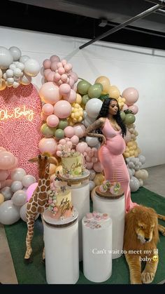 a woman in a pink dress standing next to balloons and giraffes