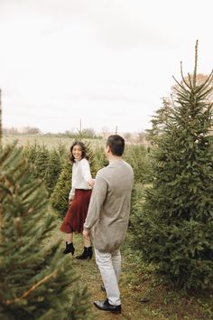 a man and woman walking through a christmas tree farm