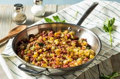 a pan filled with food sitting on top of a table next to a wooden spoon