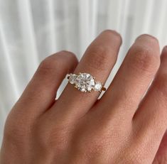 a woman's hand with a three stone ring on top of her left hand