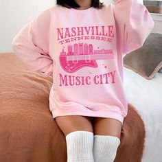 Get ready to be OBSESSED with your new 'Nashville Tennessee Music City' crewneck sweatshirt. It's the cutest and most trendy way to emit all those important Music City vibes! This is the perfect pullover for boho cowgirls, country music festivals, or country concert goers and makes a great gift for Western fashion lovers! Please note, we have intentionally added a distressed effect to this graphic, for a more vintage feel. Have a look around my shop to see what else you'll love! https://www.etsy Pink Band Merch Top For Fall, Pink Long Sleeve Band Merch Top, Pink Band Merch Sweatshirt With Letter Print, Pink Hip Hop Sweatshirt For Spring, Pink Long Sleeve Band Merch Sweatshirt, Pink Pre-shrunk Cotton Sweatshirt, Fall Concert Hoodie Sweatshirt, Pink Hip Hop Sweatshirt For Fall, Music-themed Long Sleeve Tops For Streetwear