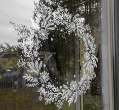 a frosted glass window with snowflakes on it's side and trees in the background