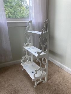 a white shelf sitting on top of a carpeted floor in front of a window